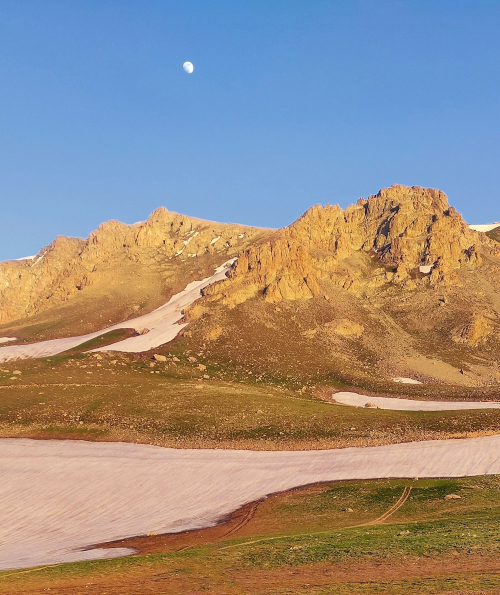 a view of a mountain range with a moon in the sky