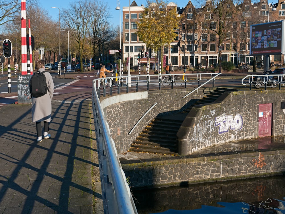 a woman walking down a street next to a river