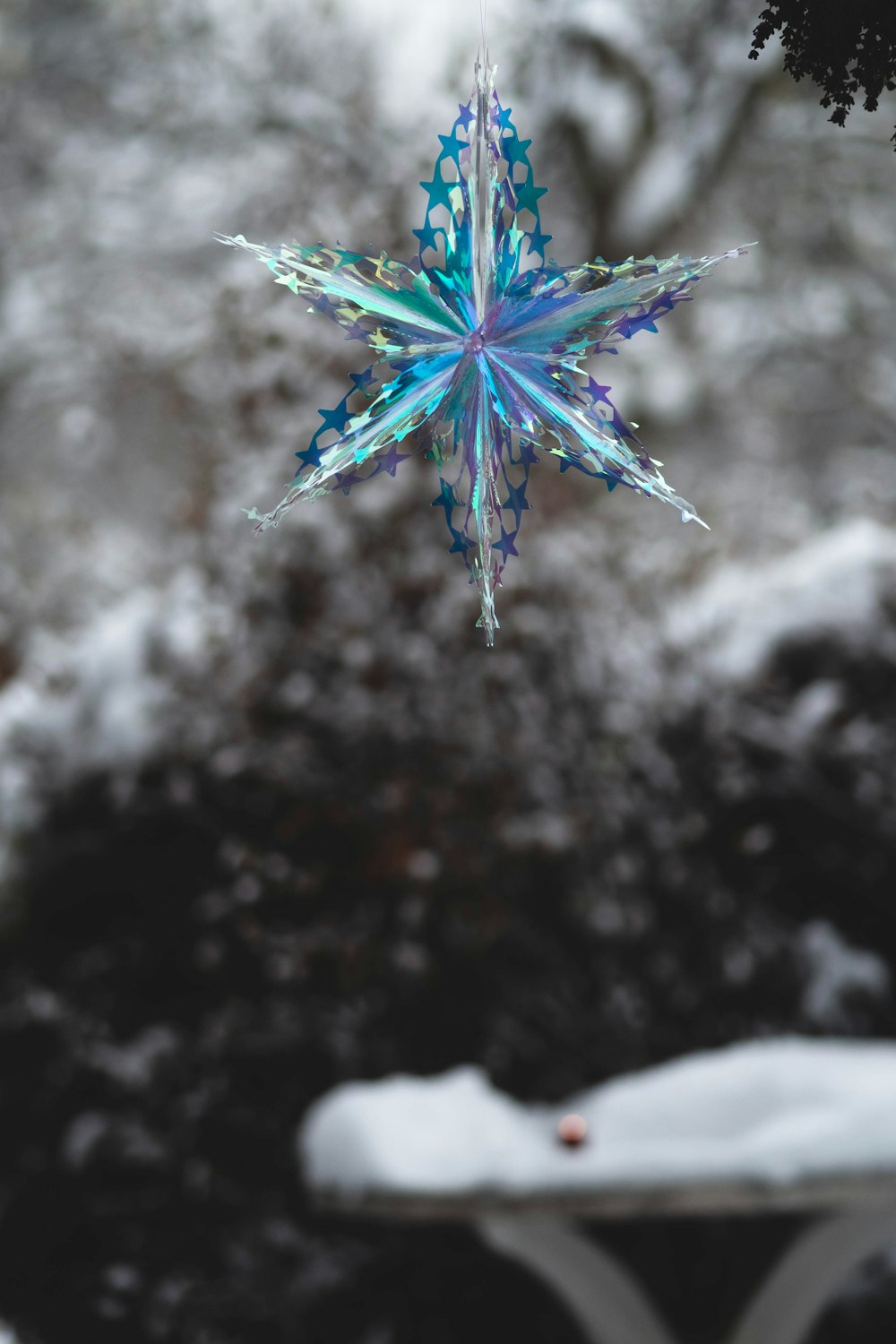 a blue snowflake hanging from a tree