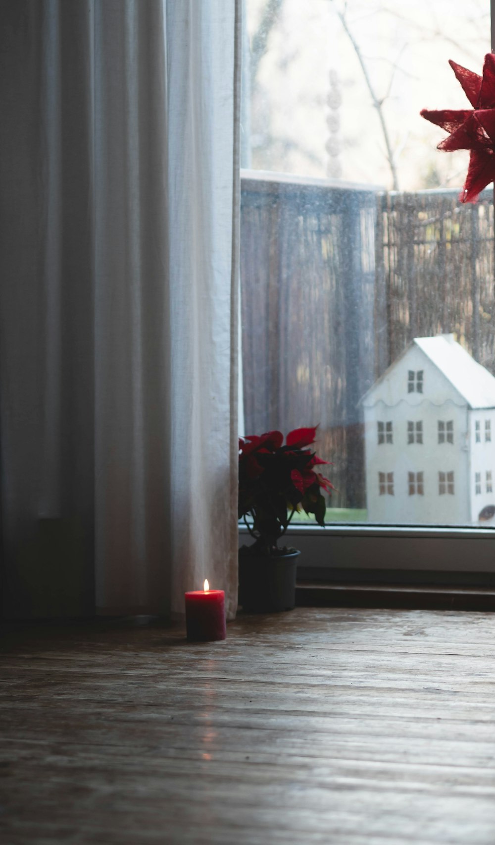 a vase with flowers on a wooden floor next to a window