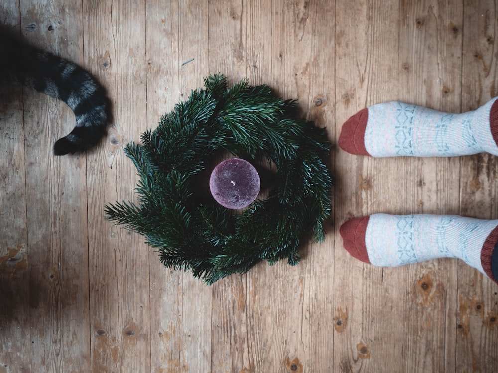 two people standing next to a wreath on a wooden floor