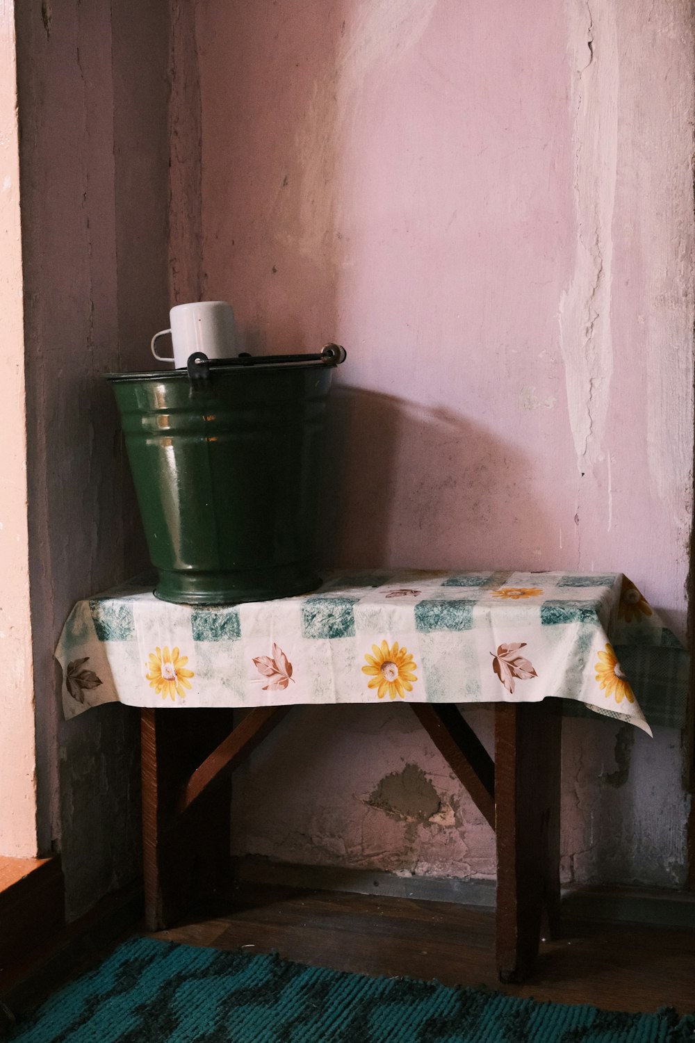 a green bucket sitting on top of a wooden bench