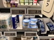A supermarket shelf displays a variety of skincare and personal care products. On the left, there are white bottles labeled Satin Care with aloe vera graphics. In the middle, blue and white bottles of Cien branded body lotions and creams are organized in boxed displays with clearly visible price tags above them. To the right, razor packs are neatly arranged, also marked with the Cien brand. The shelf is well-organized with different product categories neatly segregated.