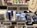 A supermarket shelf displays a variety of skincare and personal care products. On the left, there are white bottles labeled Satin Care with aloe vera graphics. In the middle, blue and white bottles of Cien branded body lotions and creams are organized in boxed displays with clearly visible price tags above them. To the right, razor packs are neatly arranged, also marked with the Cien brand. The shelf is well-organized with different product categories neatly segregated.