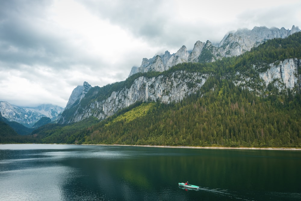 a boat floating on top of a lake surrounded by mountains