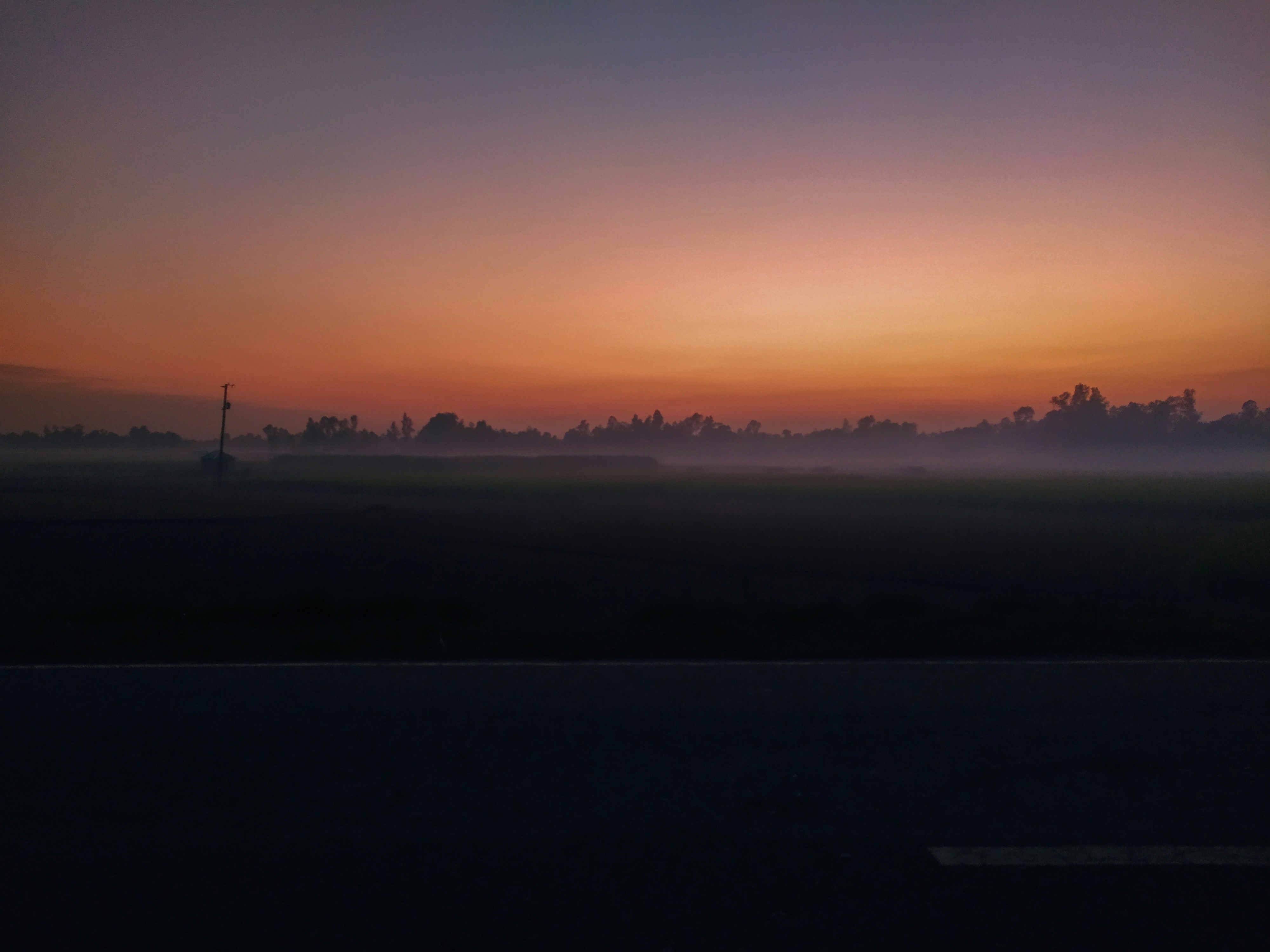 the sun is setting over a foggy field