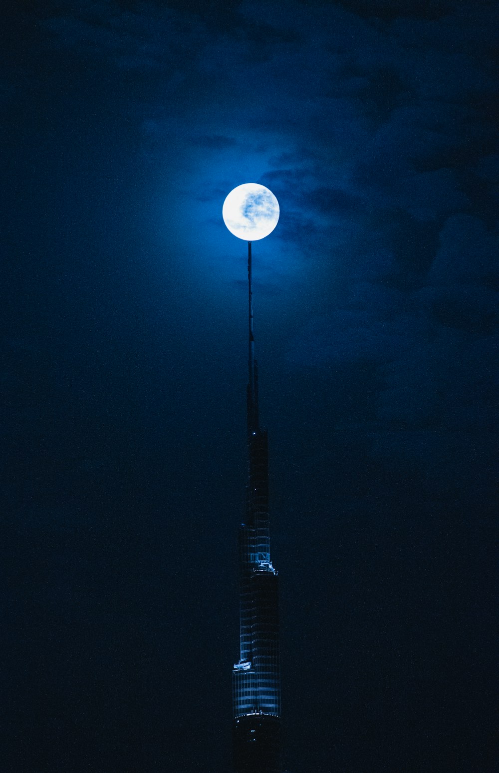a tall building with a full moon in the sky