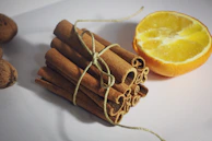 a pile of cinnamon sticks next to an orange