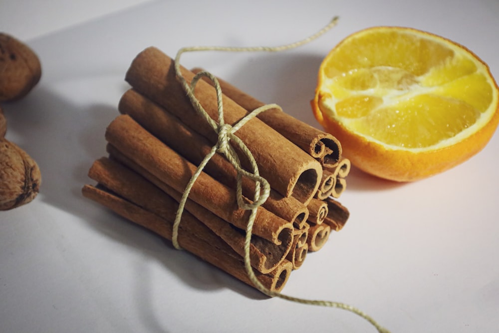 a pile of cinnamon sticks next to an orange