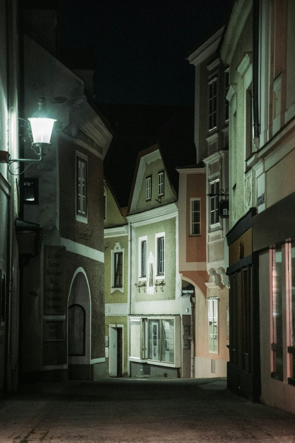 a dark alley with a clock on the side of it