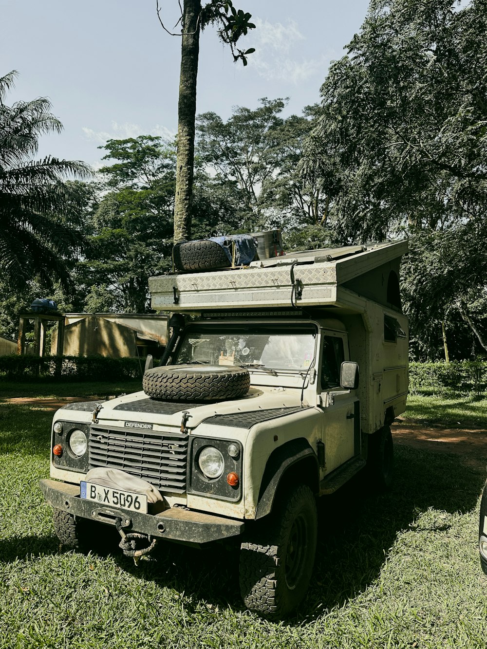 a military truck parked in the grass near a tree