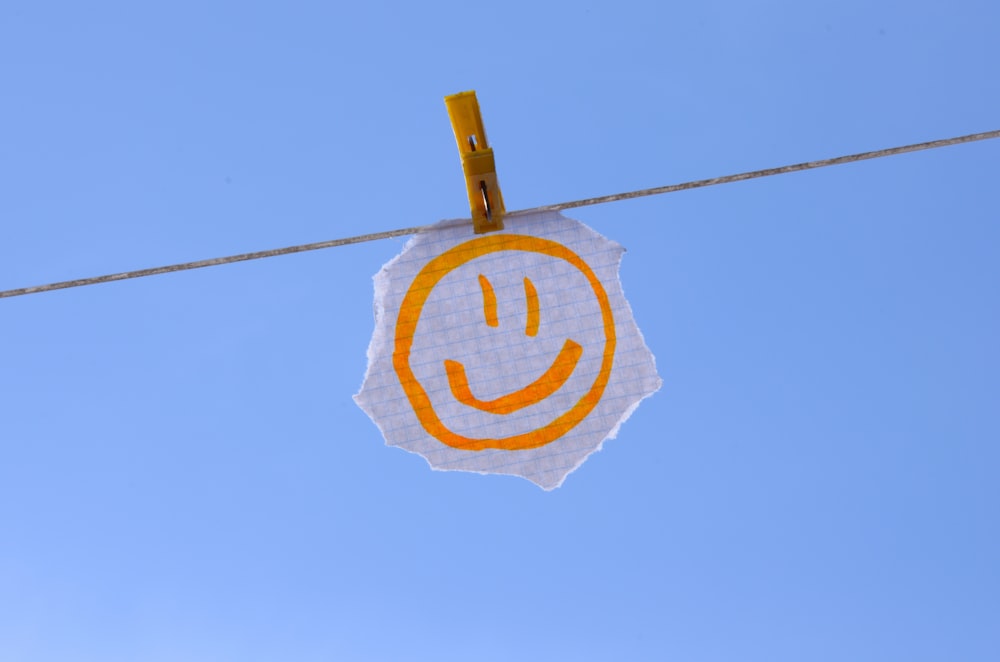 a smiley face sign hanging on a clothes line