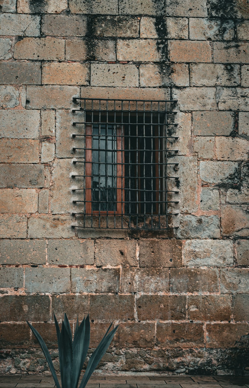 a brick wall with a window and bars on it