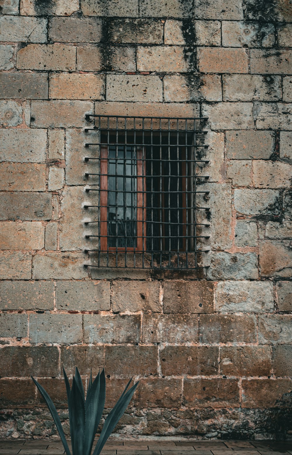 un muro di mattoni con una finestra e delle sbarre
