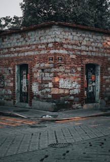a brick building with two doors and a tree