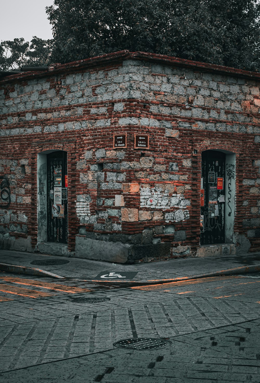 a brick building with two doors and a tree