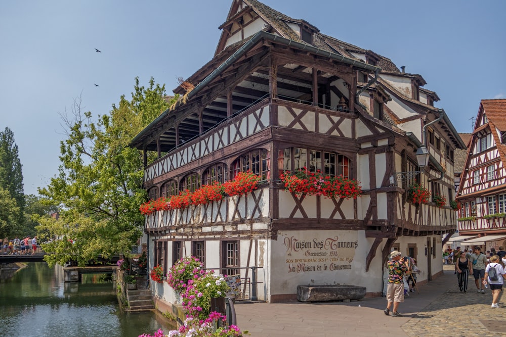 a group of people walking past a building next to a river