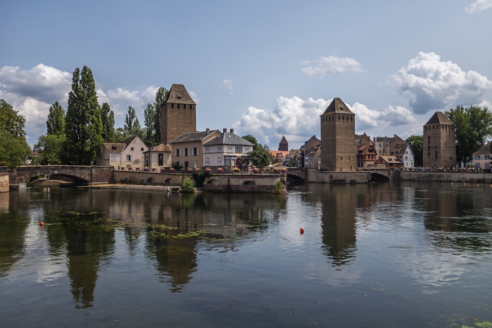 a body of water with buildings and a bridge in the background