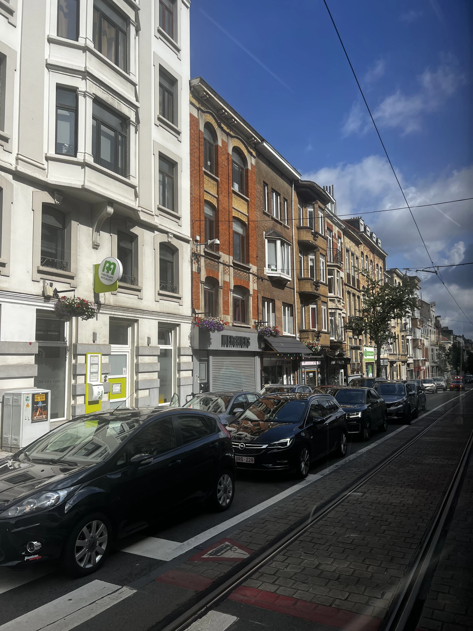 A row of parked vehicles beside brick buildings in Brussels
