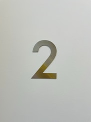 a white wall with a metal number two on it