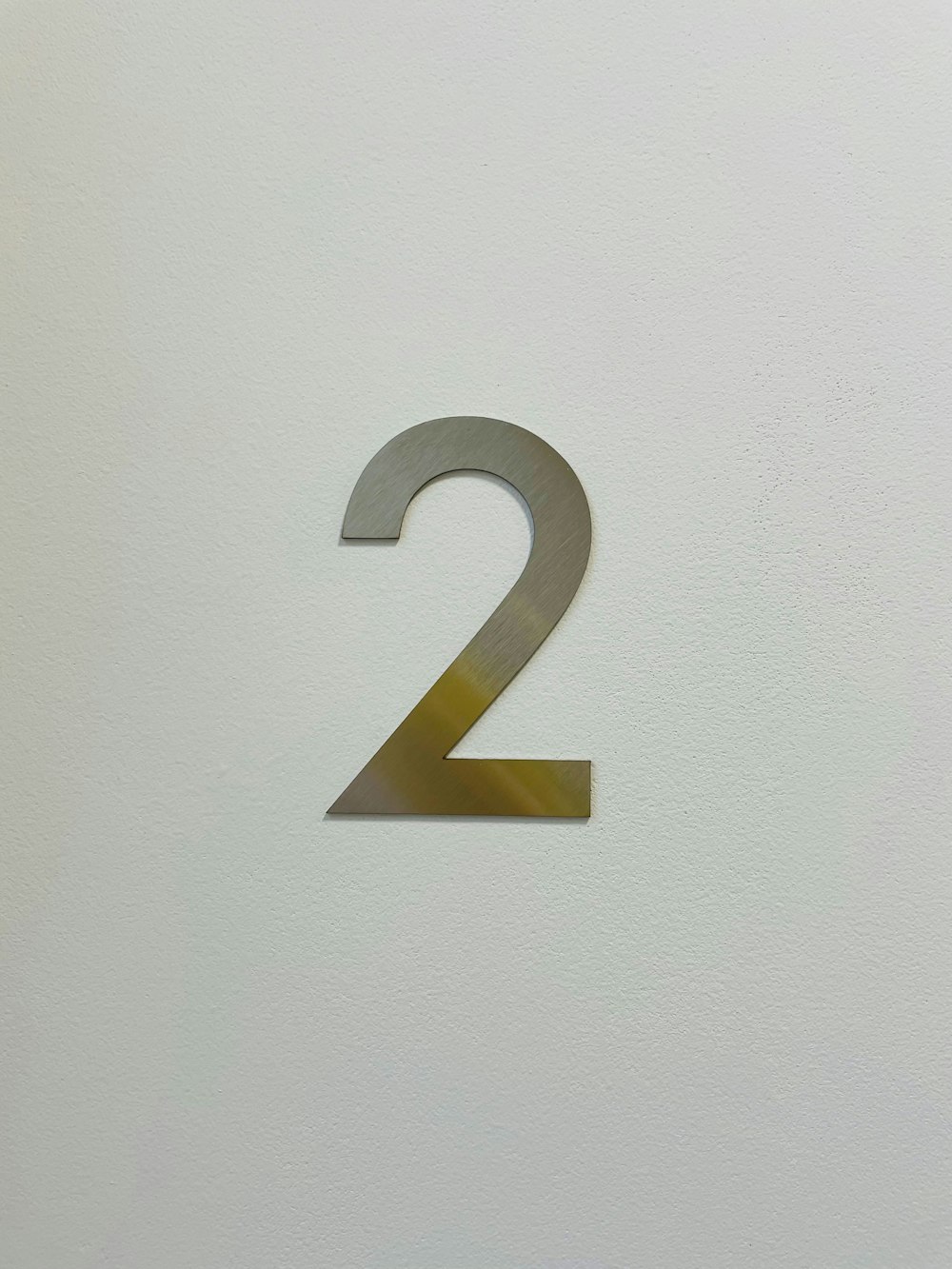 una pared blanca con un número dos de metal en ella