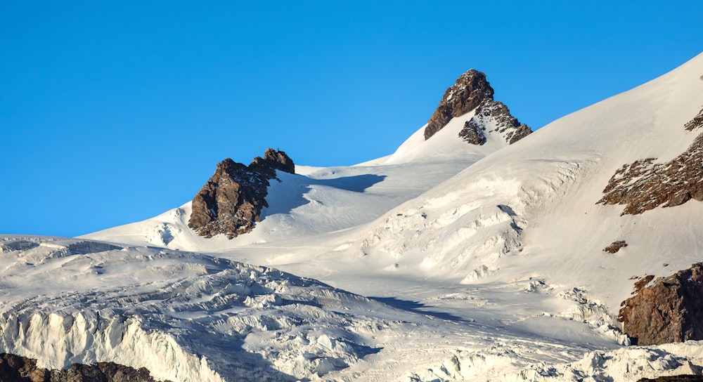 a large mountain covered in snow under a blue sky