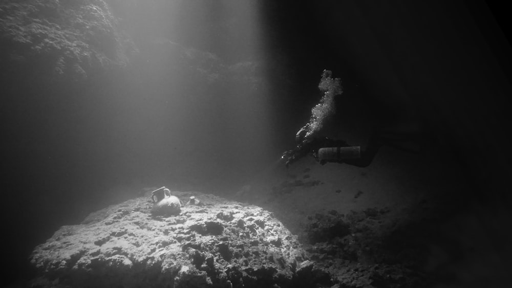 a person swimming in the water near a rock