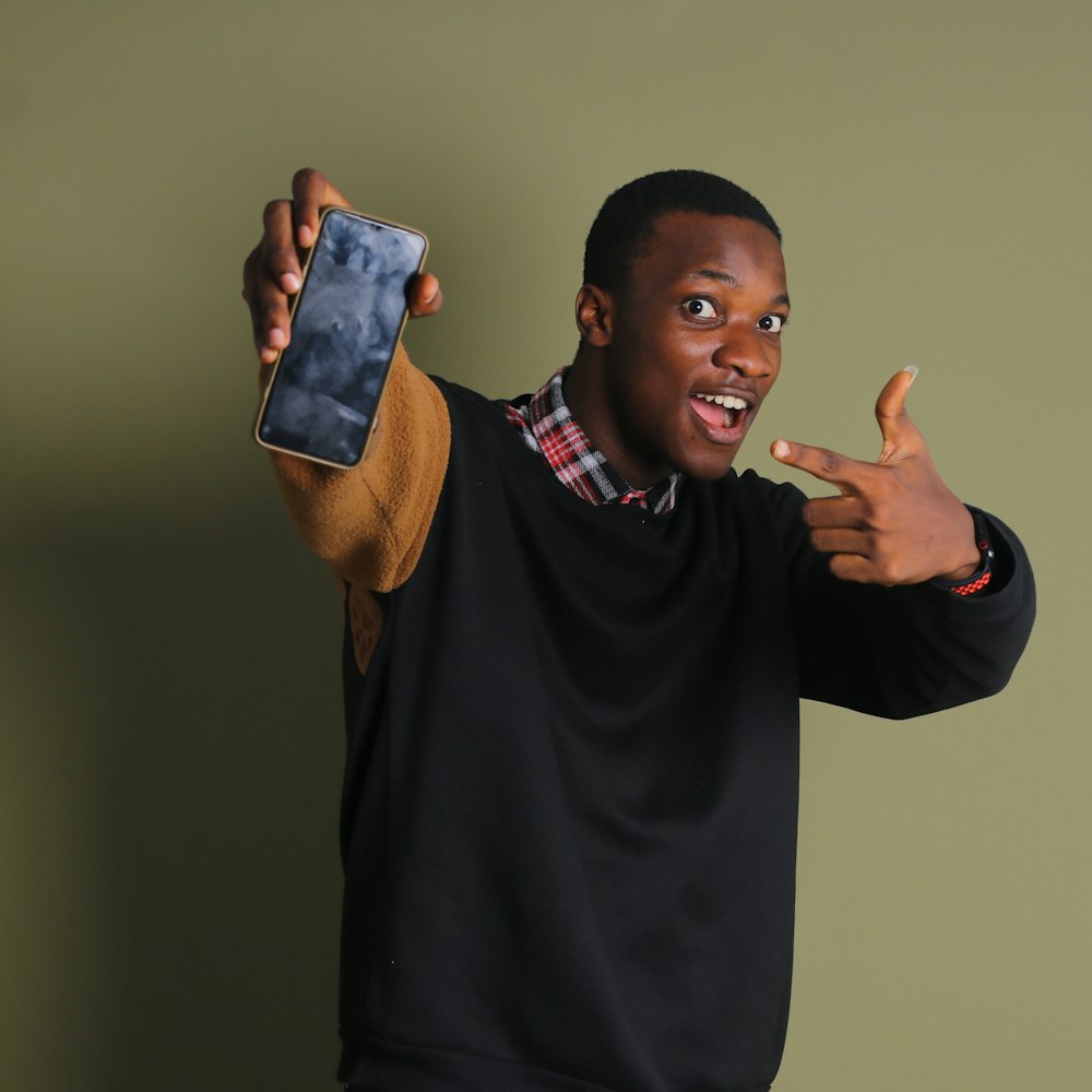 a man holding a cell phone and pointing to the camera