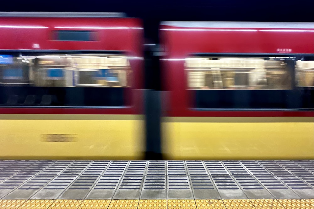 a red and yellow train traveling past a train station