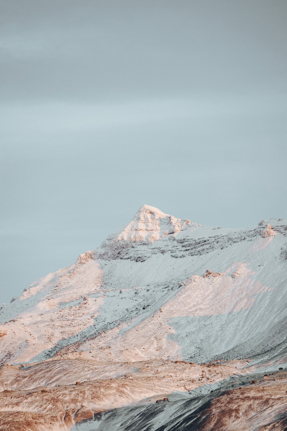 a mountain covered in snow under a cloudy sky