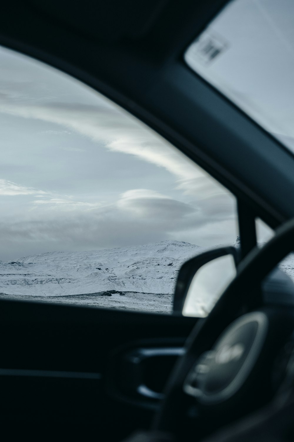 a view of a snowy mountain from inside a car