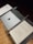 A music stand holds a closed laptop with an apple logo, a baton, and sheet music titled 'Troisième Symphonie' by Pierre Wissmer. The stand is set on a wooden floor.