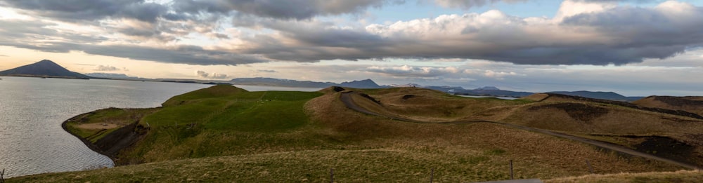 un grande specchio d'acqua seduto accanto a una collina verde lussureggiante