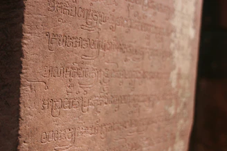 A softly glowing ancient Harappan seal resting on a dark sandstone surface with subtle terracotta highlights.