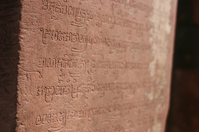 A softly glowing ancient Harappan seal resting on a dark sandstone surface with subtle terracotta highlights.