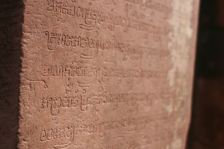 Ancient African script carved into stone, glowing softly in natural light.
