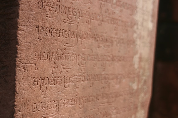 A close-up of ancient Eʋe script carved into stone, bathed in warm sunlight.