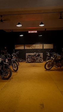 Dark industrial motorcycle workshop with custom bikes lined up under moody lighting.