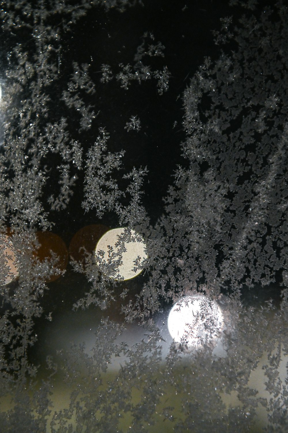 a close up of a frosted window with a street light in the background
