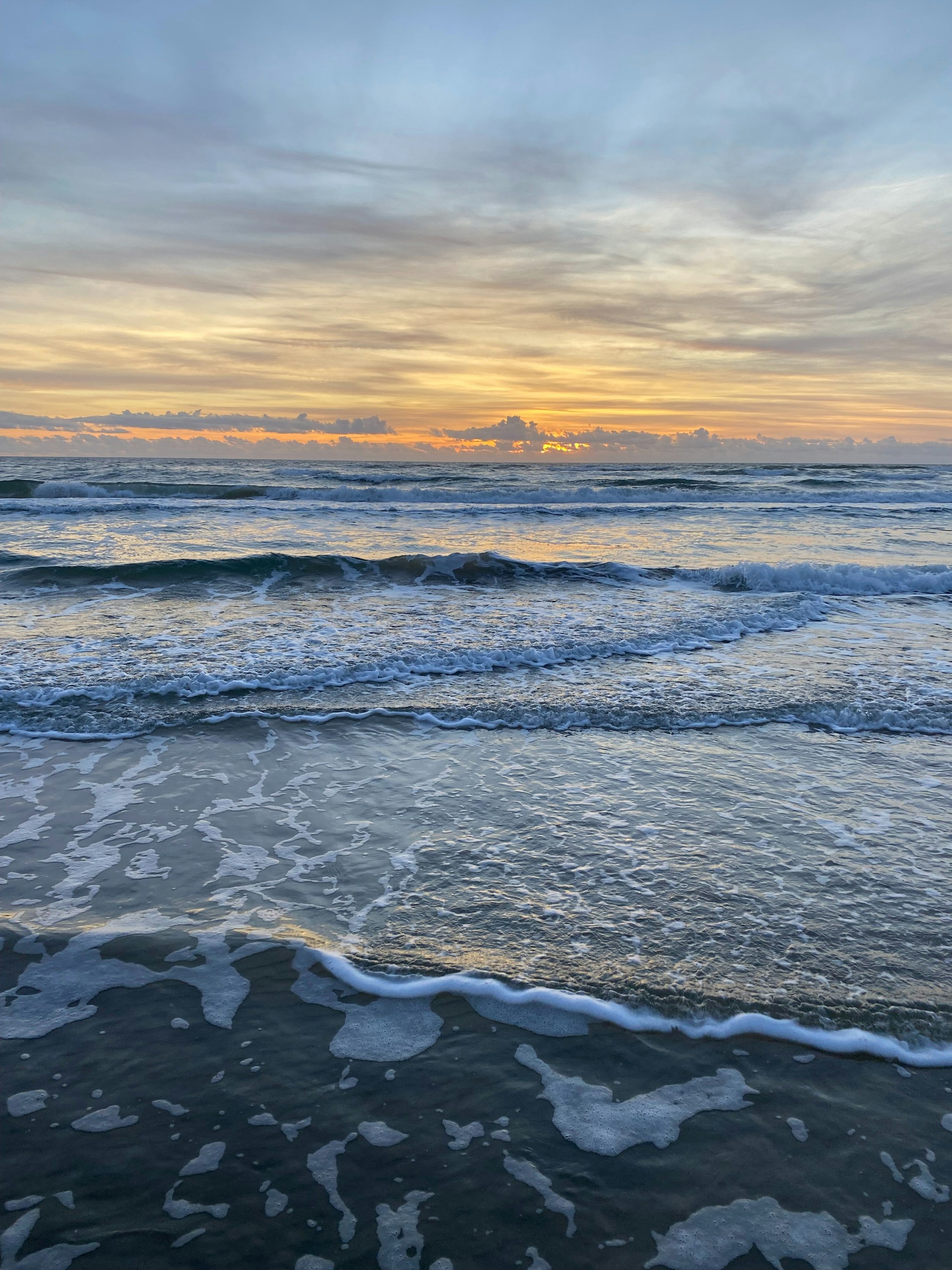 A serene sunrise over a beach with soft waves, creating a peaceful atmosphere.