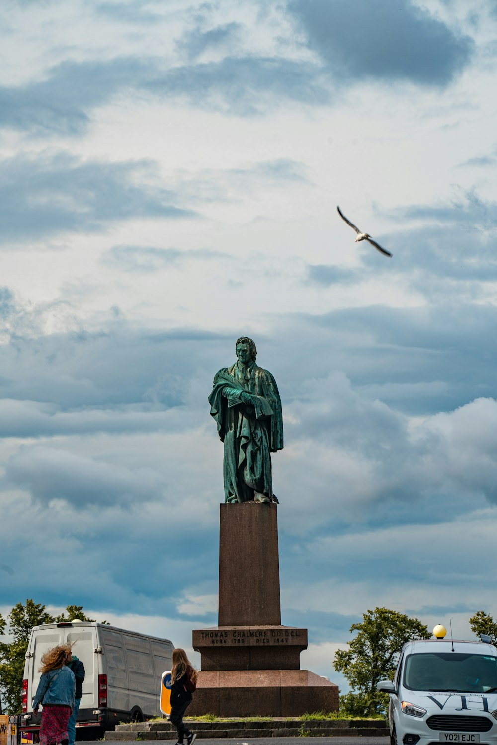 uma estátua de um homem com um pássaro voando no céu