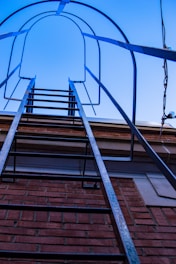 A sturdy airplane-style ladder set up outdoors against a building.