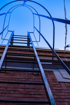 A sturdy airplane-style ladder set up outdoors against a building.