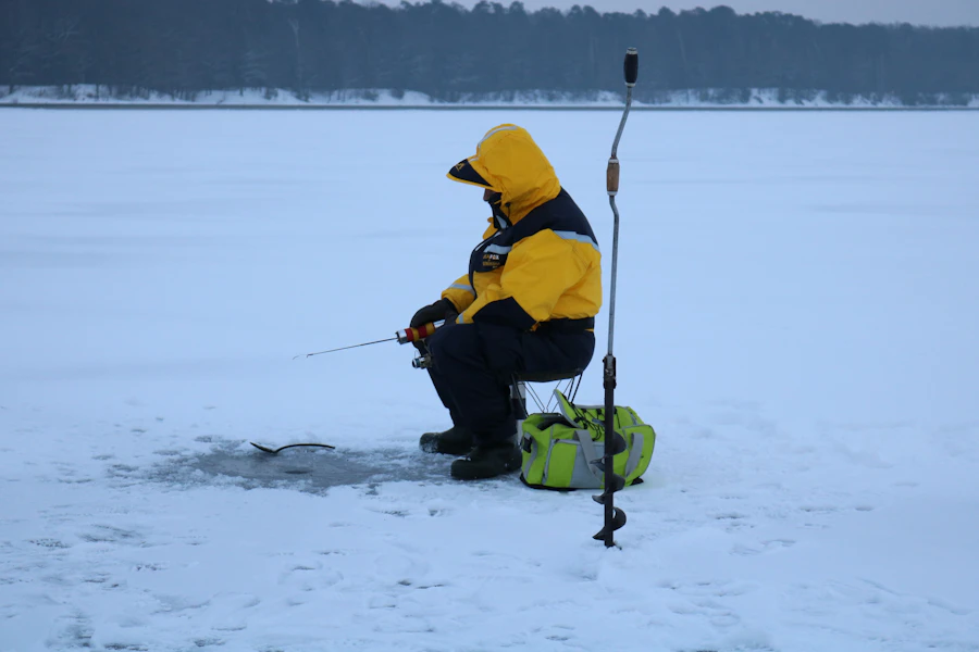 Angler in a yellow jacket fishing on a frozen lake