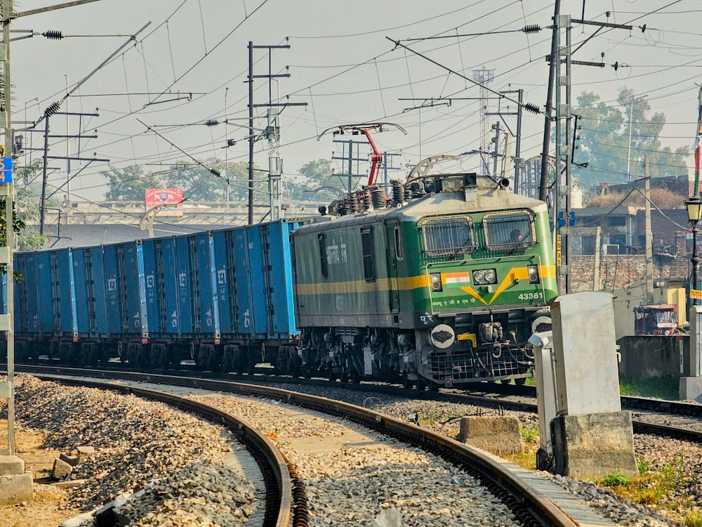 a green and blue train traveling down train tracks