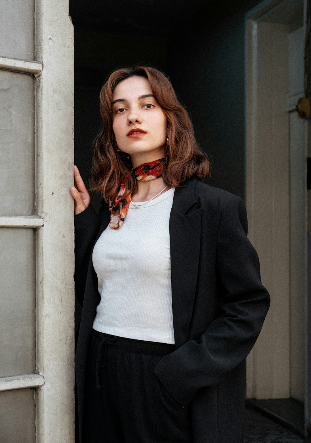 a woman standing in a doorway with a tie around her neck