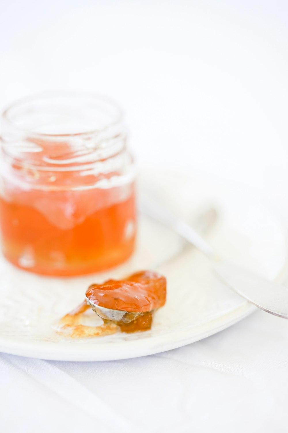 a white plate topped with a jar of jelly and a spoon
