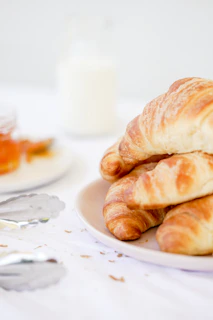 A minimalist plate with a perfectly toasted croissant next to a small jar of homemade jam.