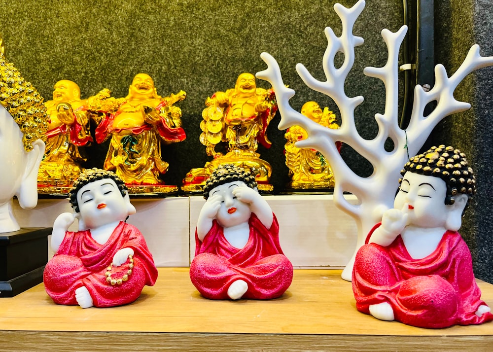 a group of buddha statues sitting on top of a wooden table