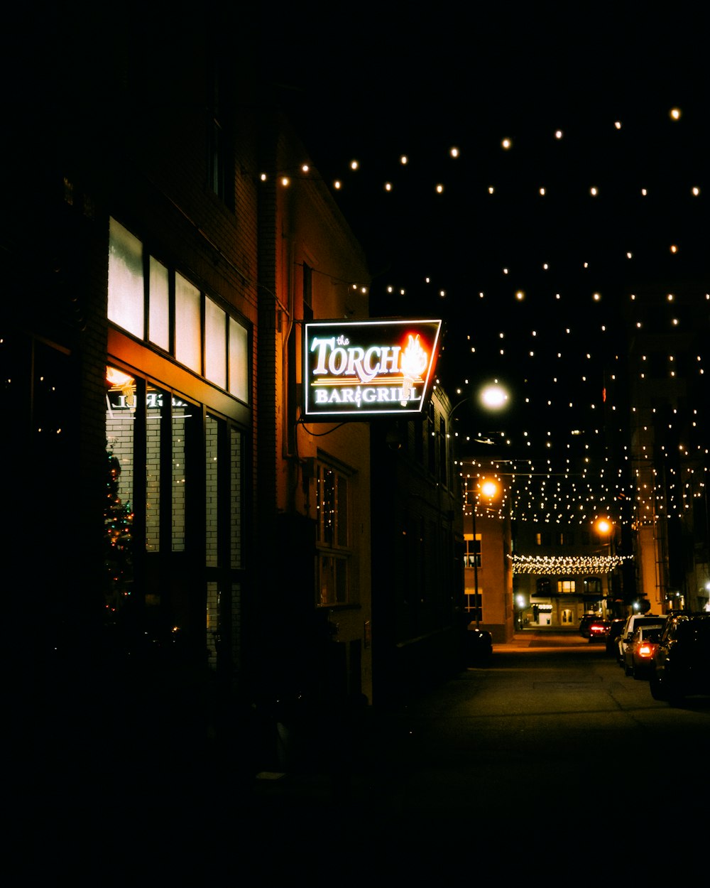 a dark street at night with lights strung overhead